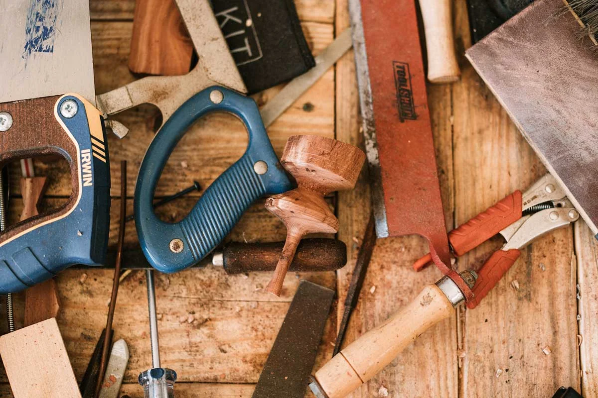 Handsaws, pliers and chisels scattered across a workbench