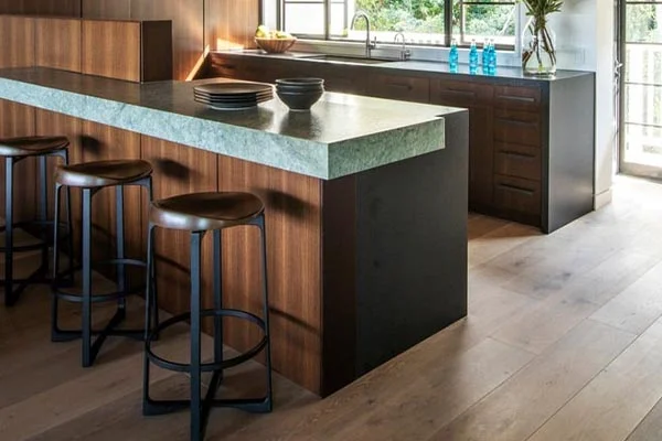 Grey-washed oak floor beside a walnut kitchen island and stools