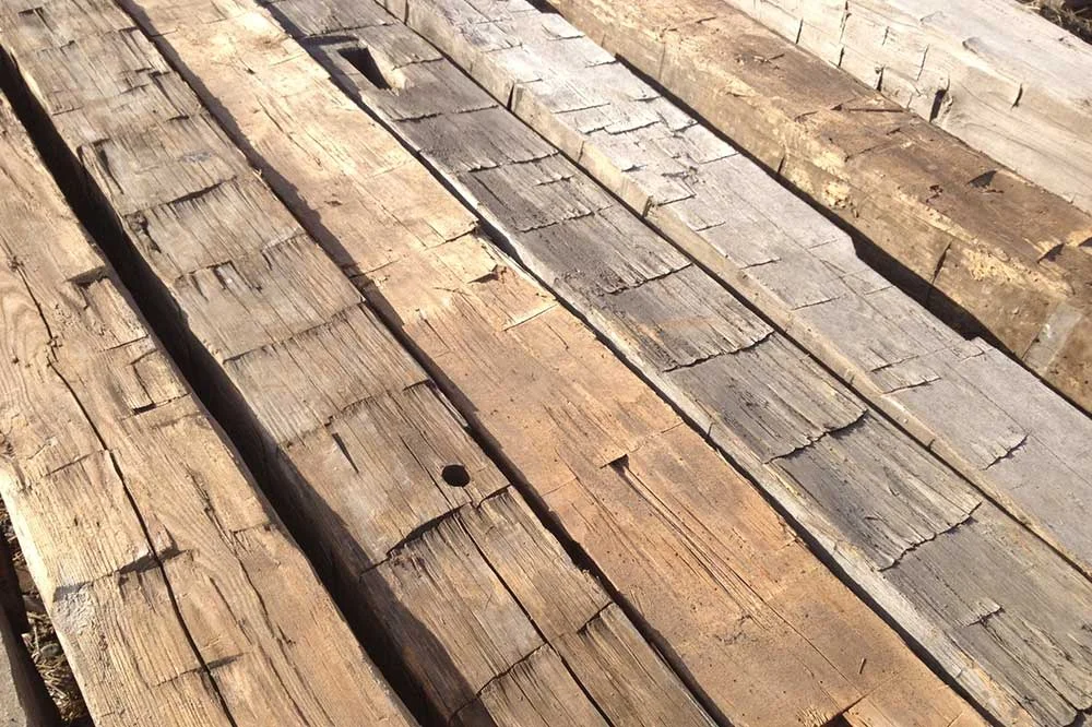 Hand-hewn reclaimed barn beams laid side by side in sunlight