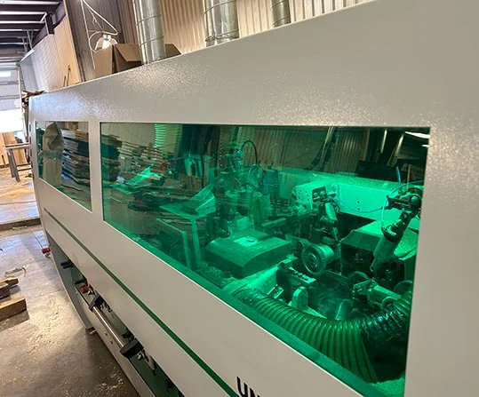Green-lit cutterheads visible through the guard window of a moulder