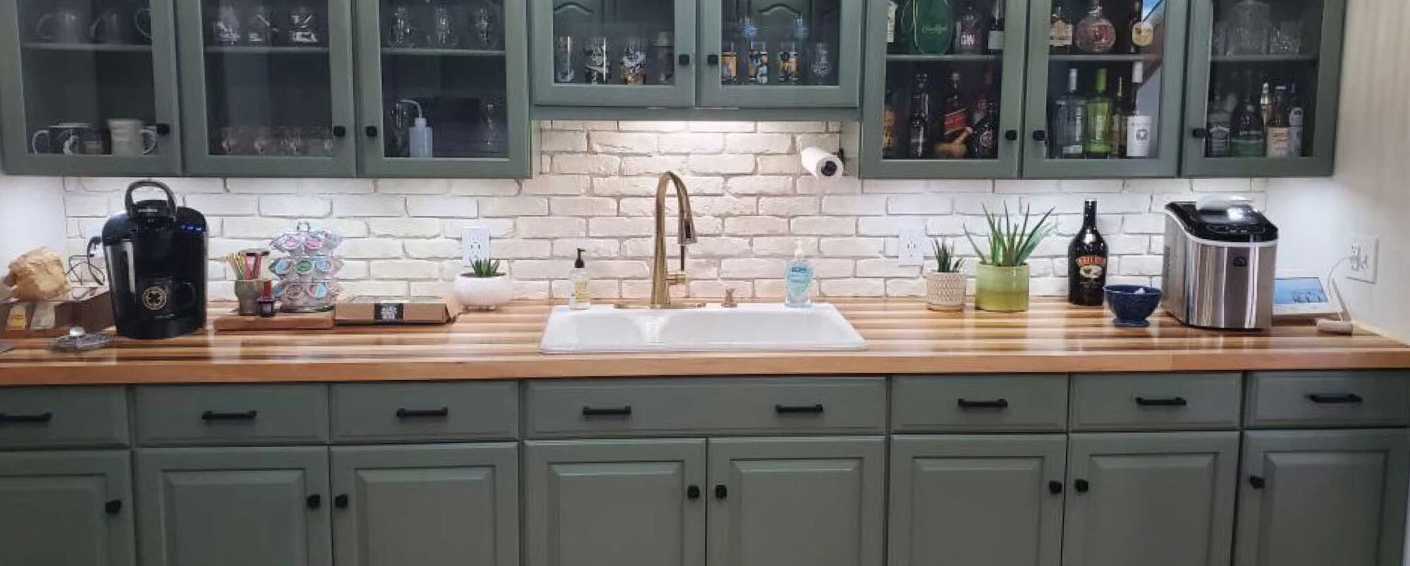 Maple butcher block countertop in a kitchen with sage green cabinets